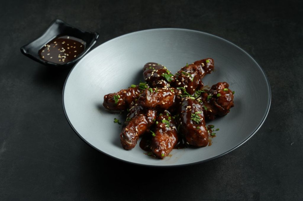 Saucy Korean-style chicken wings topped with sesame seeds on a plate