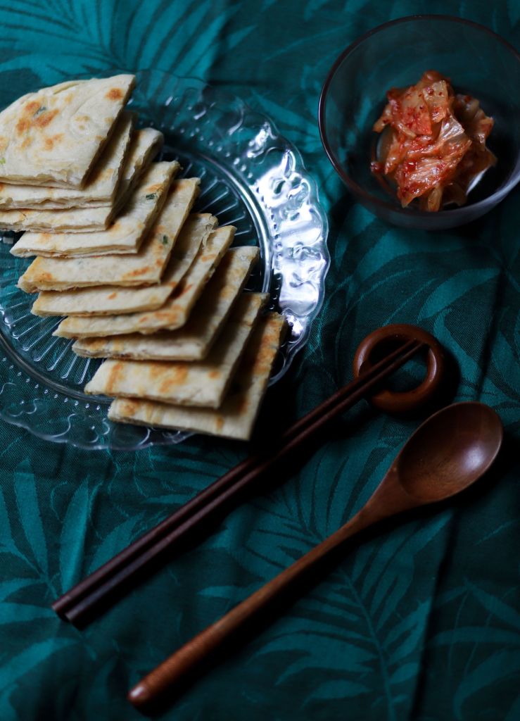 Korean kimchi pancakes on a glass plate with chopsticks