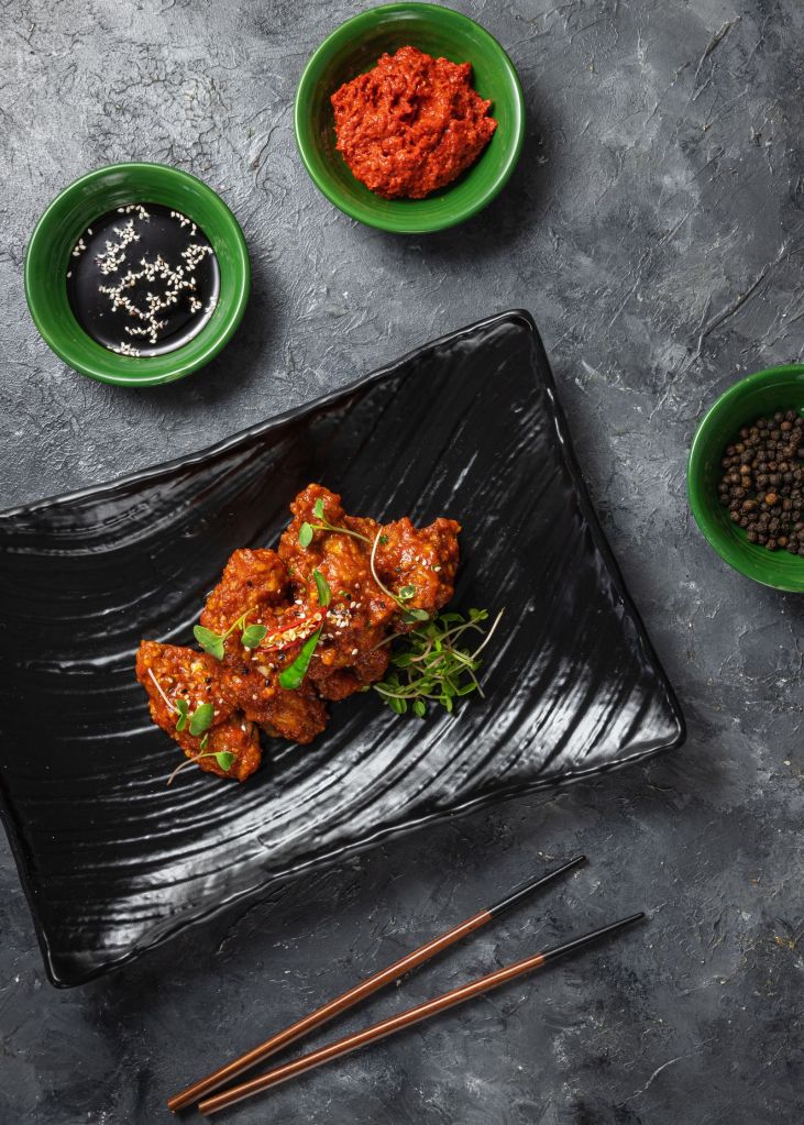 Spicy red-glazed Korean chicken on a black plate