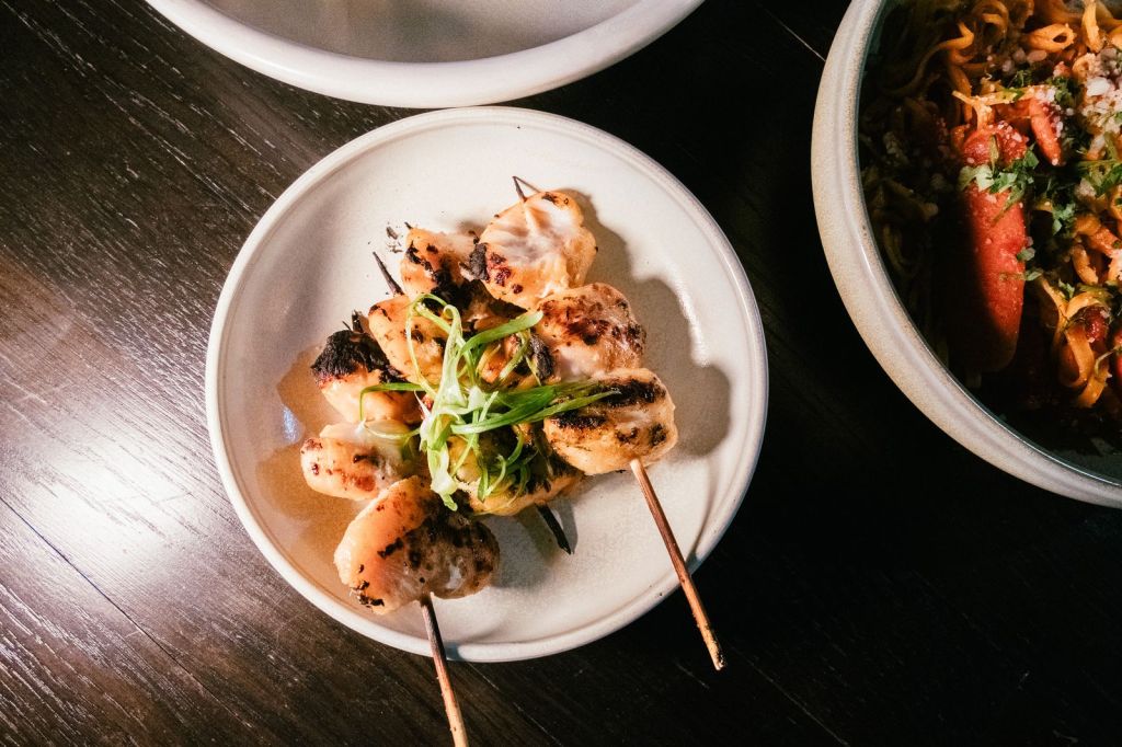 Grilled chicken and scallion skewers glazed with sauce on a plate