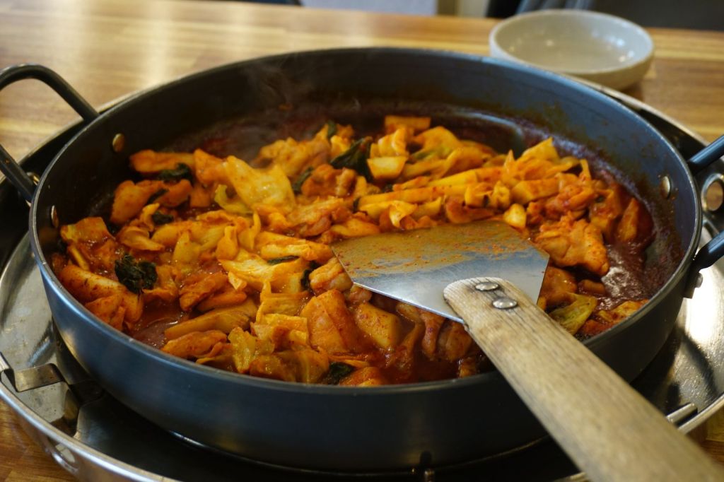 Dakgalbi spicy Korean stir-fried chicken with vegetables cooking in a large pan