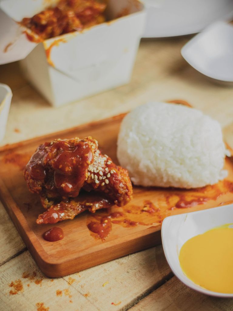 Sticky sweet and spicy Korean chicken bites topped with sesame seeds served with rice