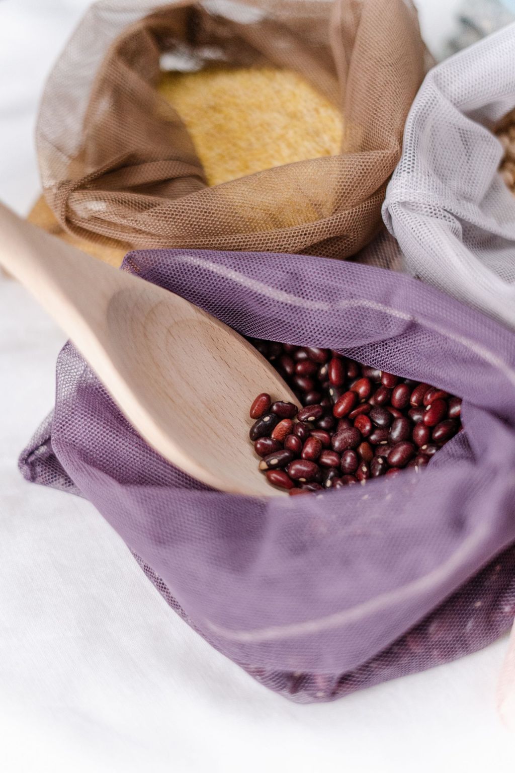 Dried red adzuki beans in a net bag with a scoop