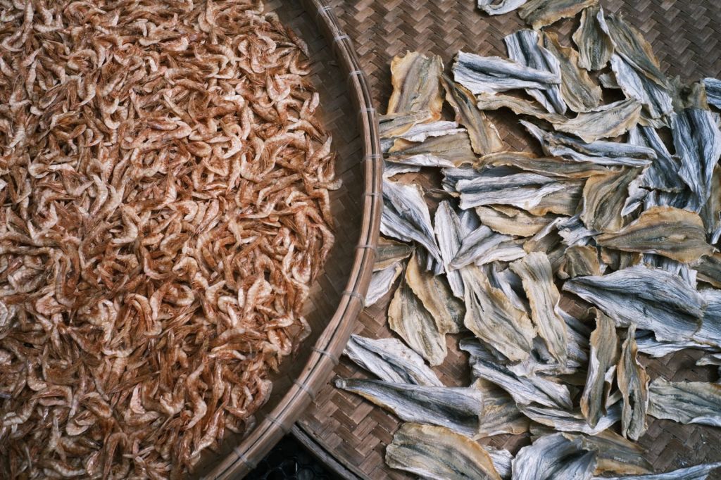 Top view of small dried shrimp and dried fish on a bamboo tray