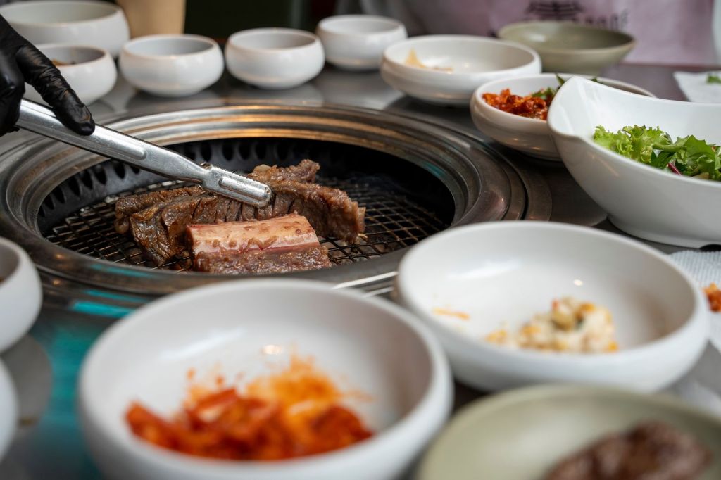 Marinated Korean BBQ ribs grilling on a tabletop grill with side dishes in Seoul