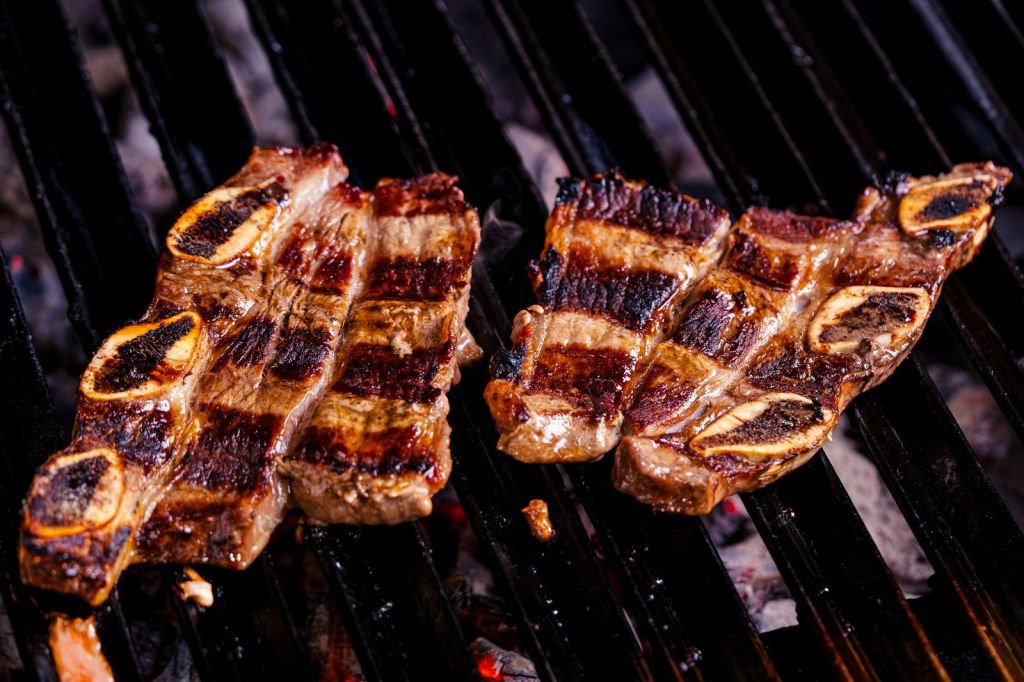 Beef short ribs grilling over charcoal, the cut used for Korean galbi