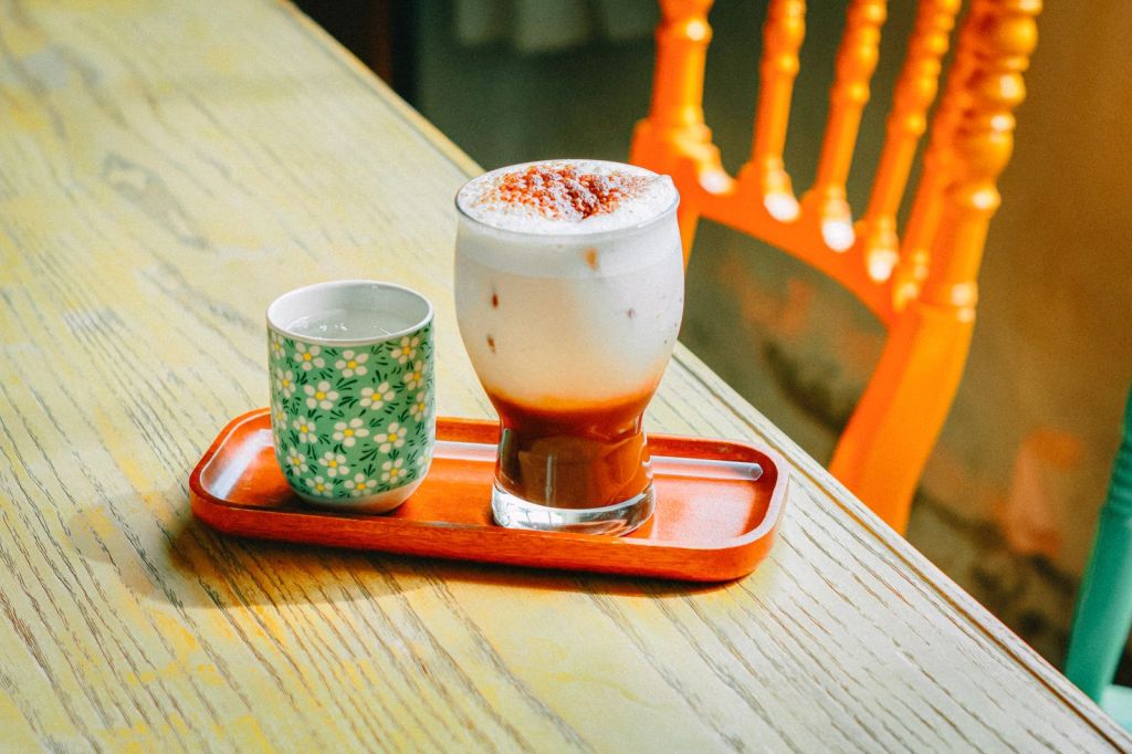 Iced milky beige drink in a glass on a wooden table