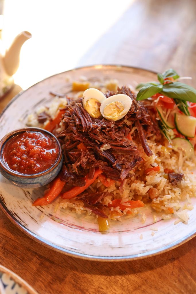 Soy-braised beef served over rice with boiled eggs and a side sauce