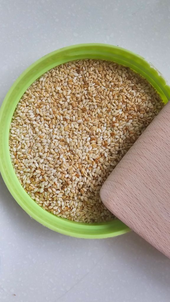 Roasted sesame seeds in a green bowl, used as Korean kkaesogeum