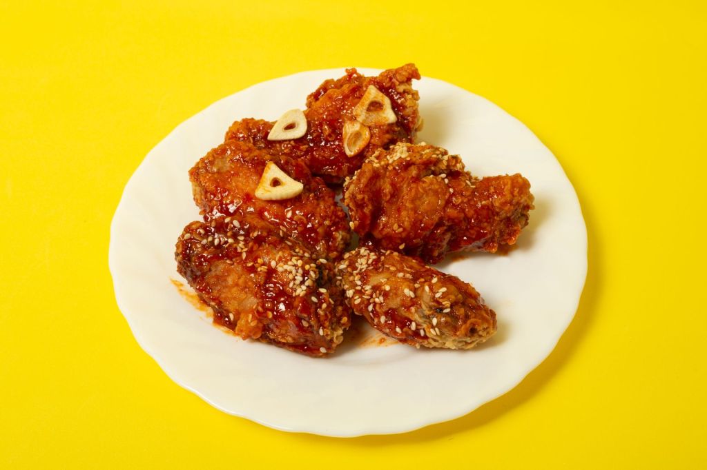 Crispy fried chicken pieces tossed in a glossy garlic sauce on a white plate