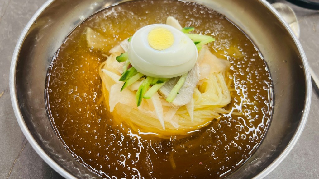 Korean cold noodles topped with a boiled egg and julienned cucumber