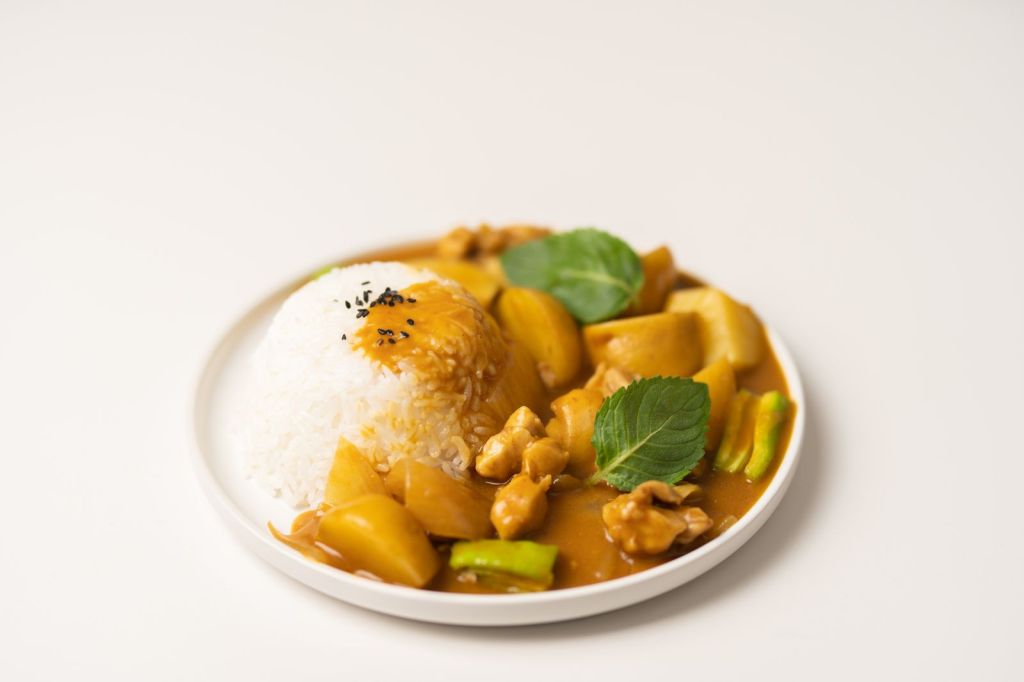 Curry rice with stewed potatoes, carrots and meat on a ceramic plate
