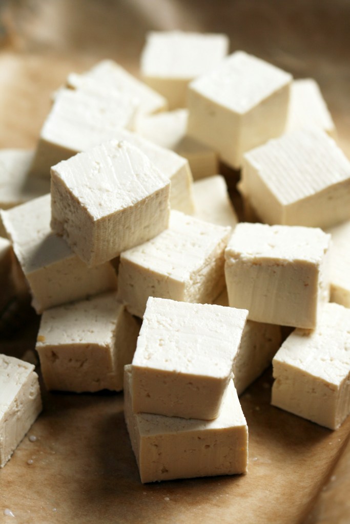 Cubes of firm tofu (dubu) piled on a wooden cutting board