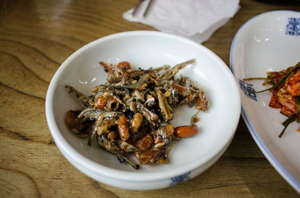 Korean side dish of glossy stir-fried anchovies and nuts in a white bowl