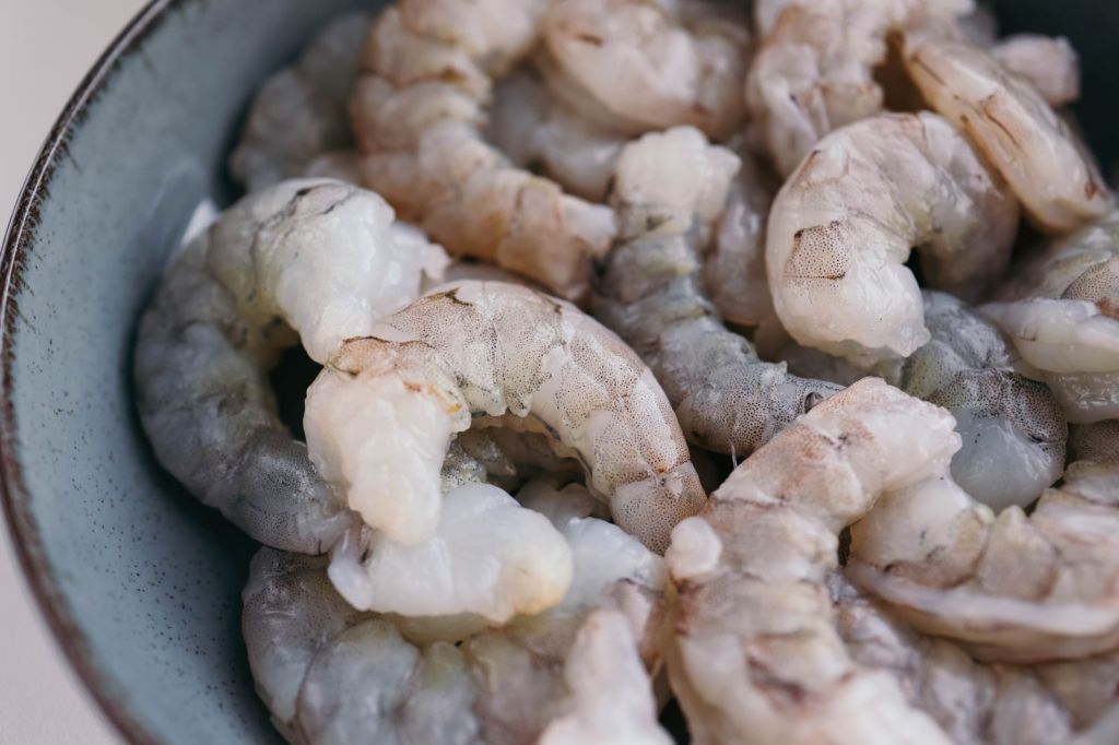 Fresh raw shrimp in a blue bowl ready for soy marinating