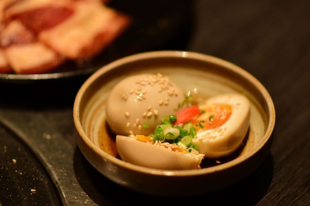 Halved soy-marinated jammy eggs topped with sesame seeds and sliced green onions