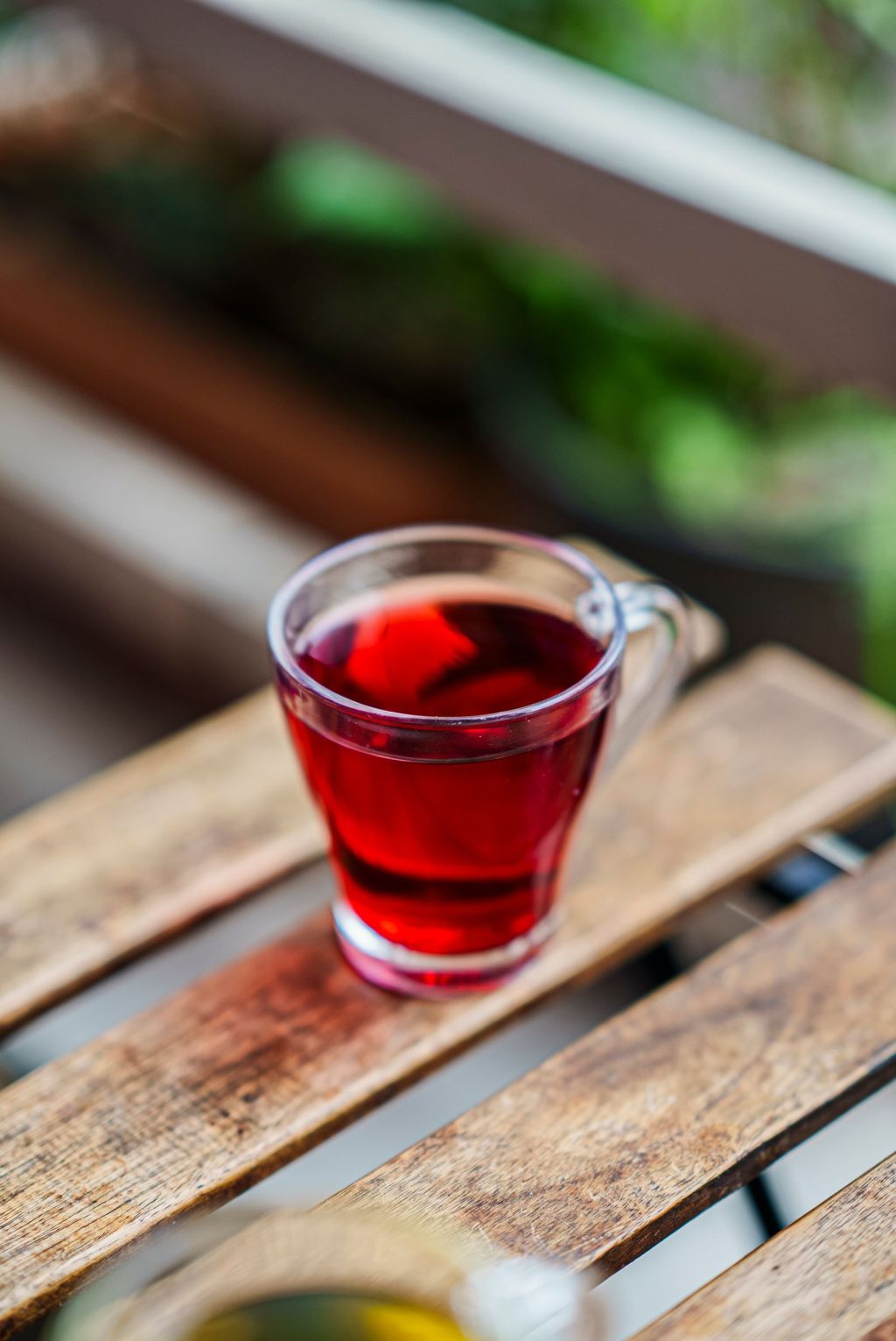 Ruby-red herbal tea in a glass cup on a wooden table, similar in color to omija tea