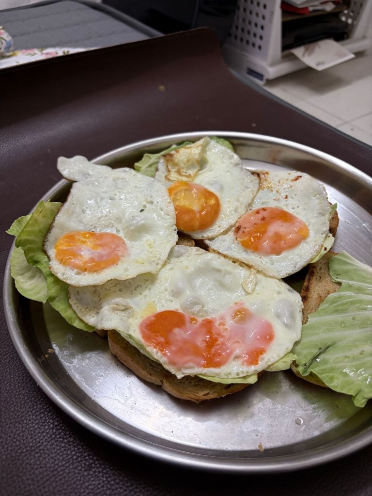 Toasted bread topped with fried egg and fresh lettuce, similar to Korean street toast