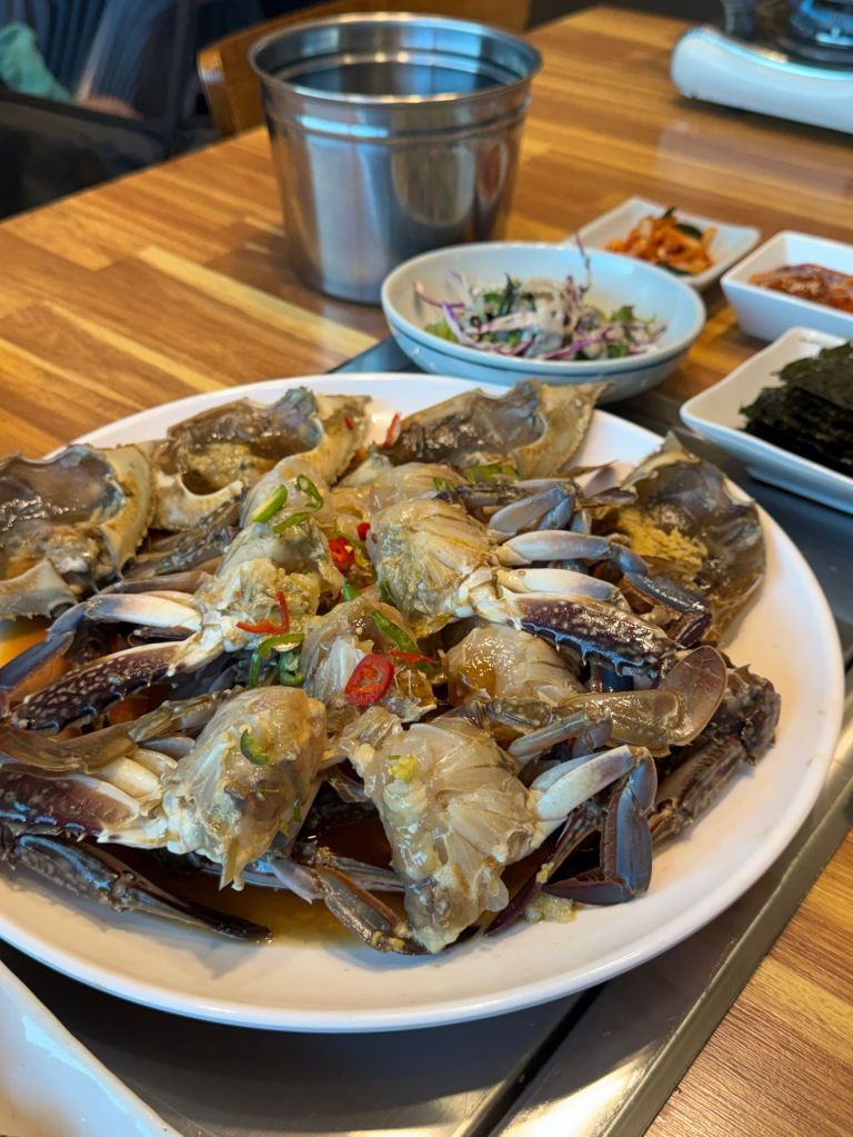 Korean marinated raw crab (gejang) served with side dishes on a wooden table