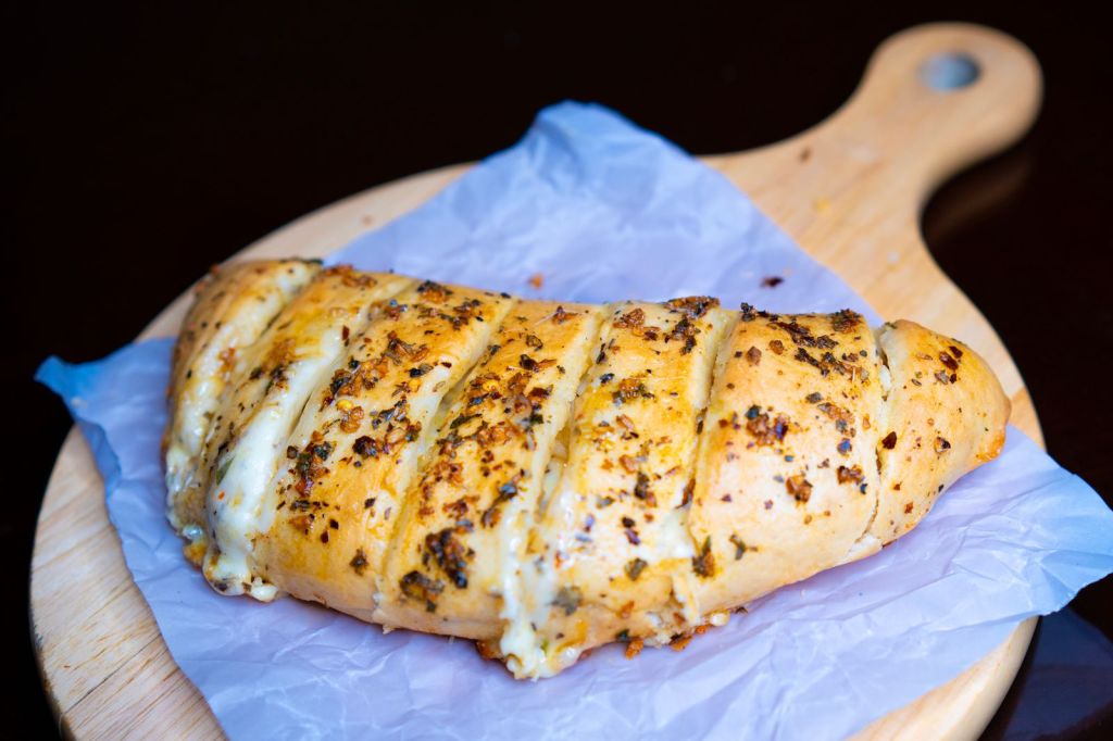 Garlic bread filled with melted cheese on a wooden board