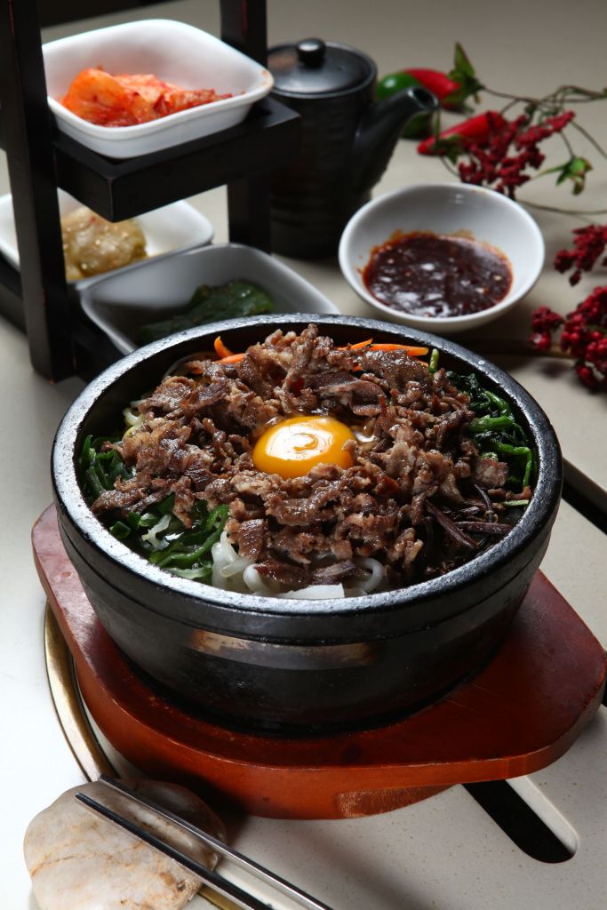 Korean bibimbap in a stone pot served with banchan side dishes