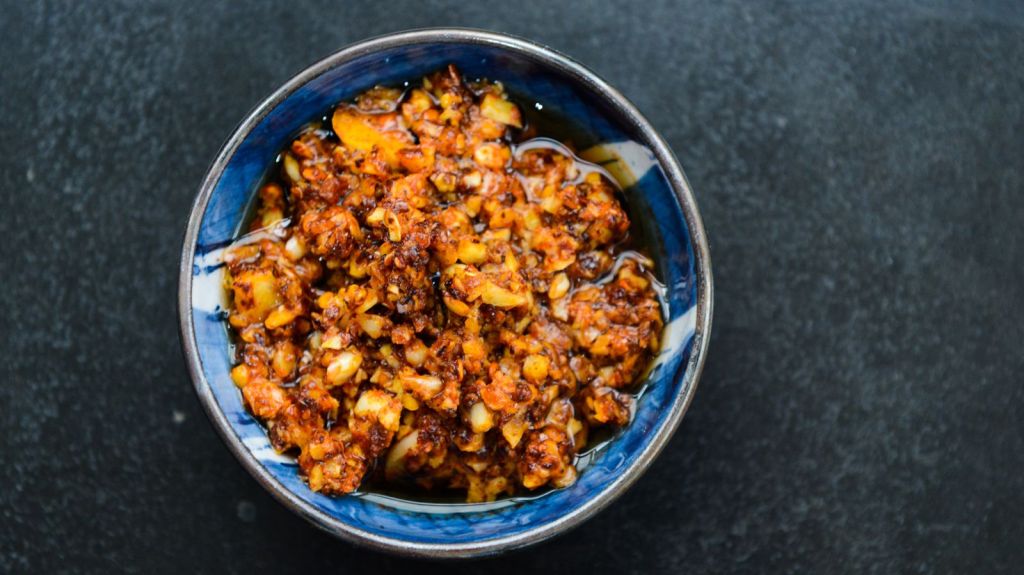 A bowl of red chili oil with garlic and chili pepper flakes
