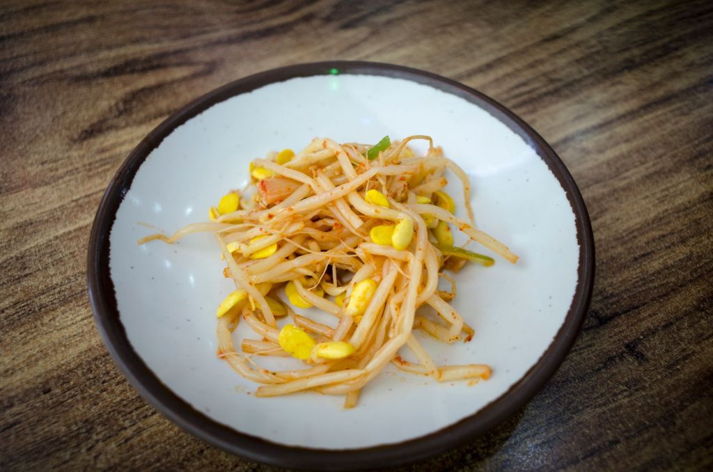 Korean soybean sprouts seasoned with soy sauce, sesame and green onion on a plate