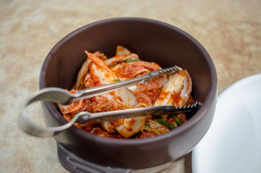 Close-up of napa cabbage kimchi coated in red chili kimchi paste in a dark bowl