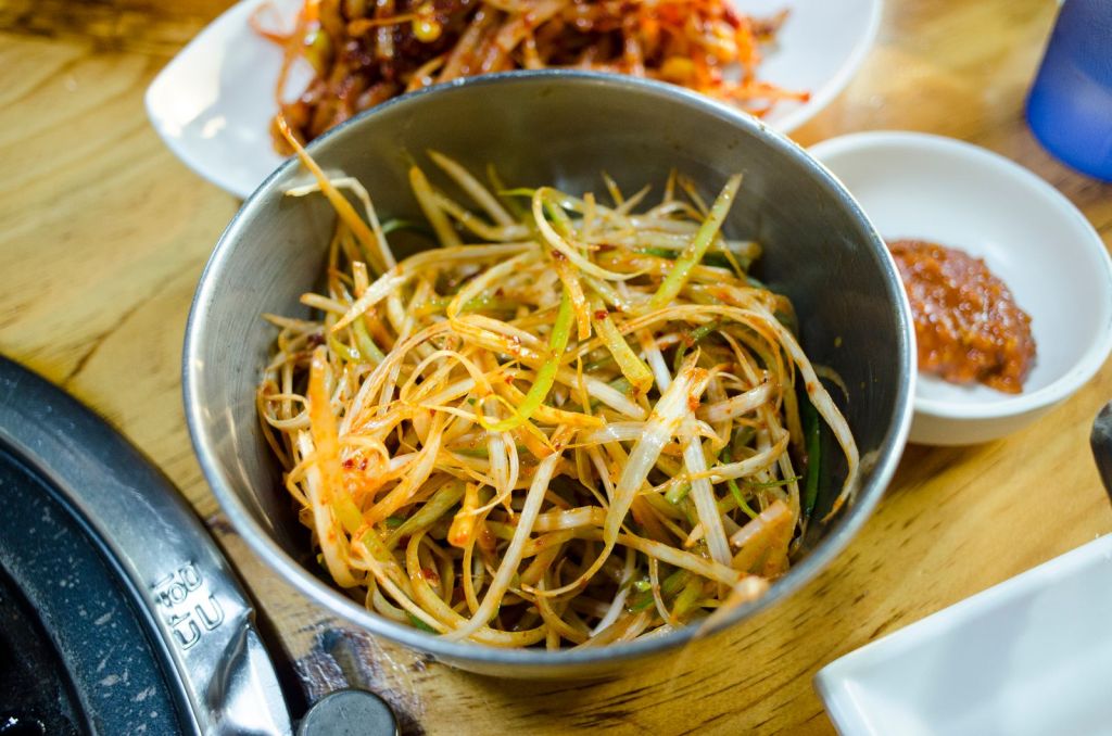Green onions coated in red Korean chili seasoning in a metal bowl