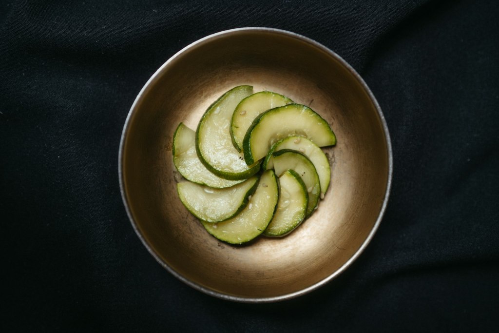 A metal bowl of sliced pickled cucumbers served as a Korean side dish