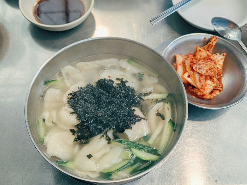 A bowl of Korean kalguksu knife-cut noodle soup served with kimchi