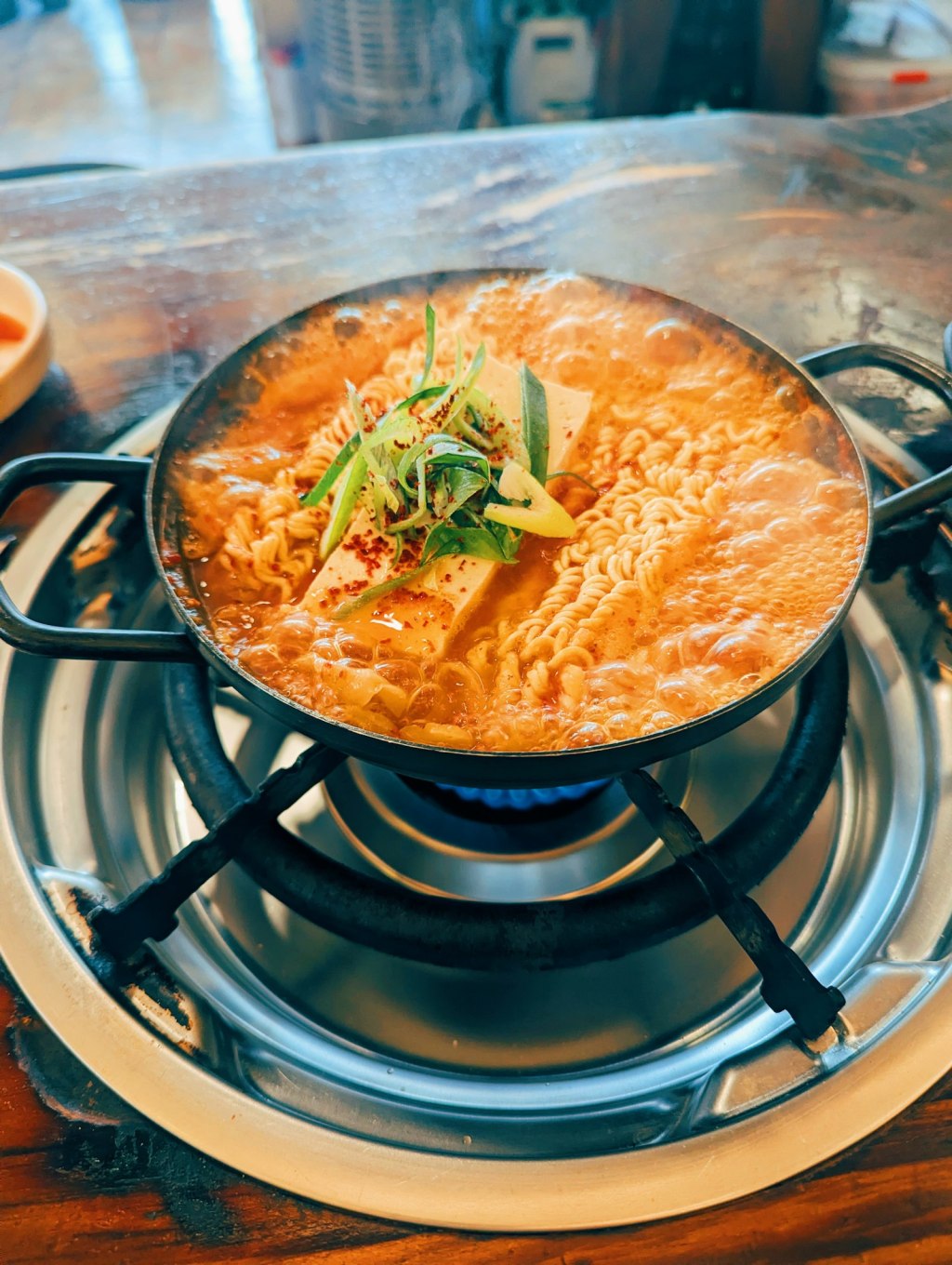 A bubbling pot of Korean budae jjigae style stew with noodles and tofu
