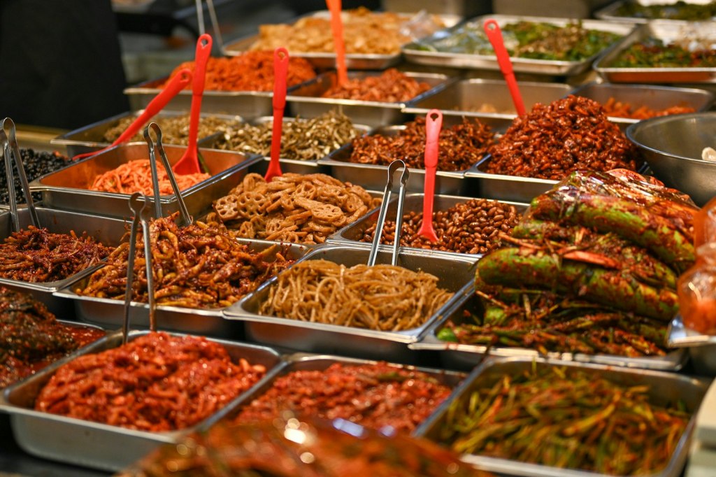 Assorted Korean banchan side dishes in metal trays at Mangwon Market, Seoul