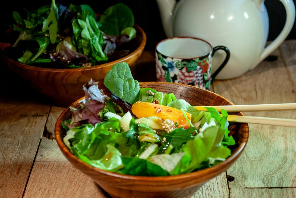 Fresh green salad served Asian style with chopsticks and a teapot