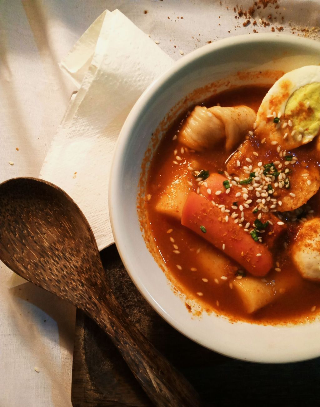 Bowl of Korean tteokbokki rice cakes in sauce garnished with sesame seeds