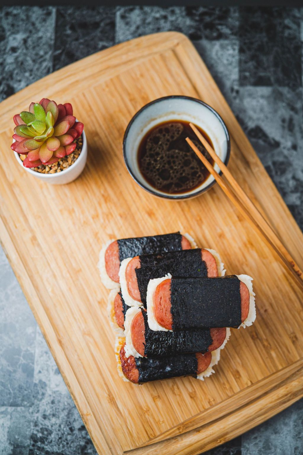 Slices of Spam on rice wrapped with seaweed, served with soy sauce