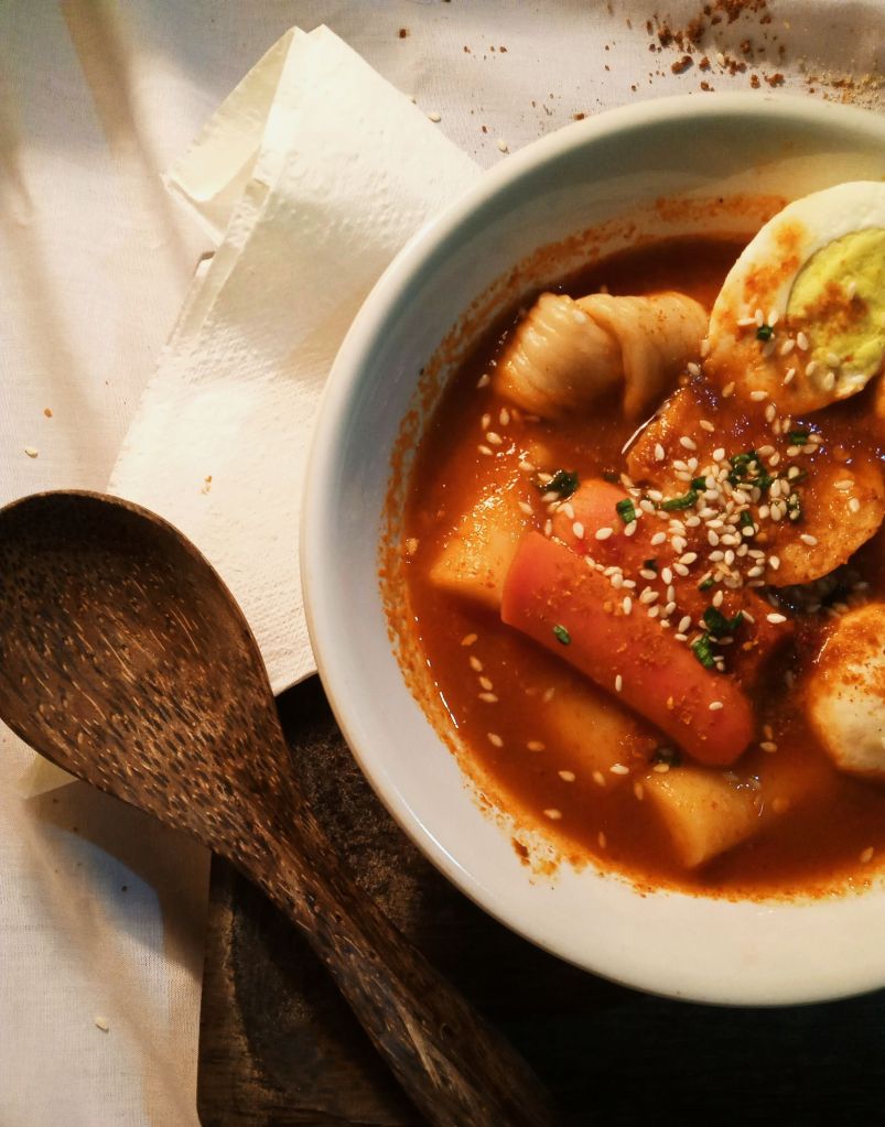 Chewy Korean rice cakes coated in red gochujang sauce with sesame seeds
