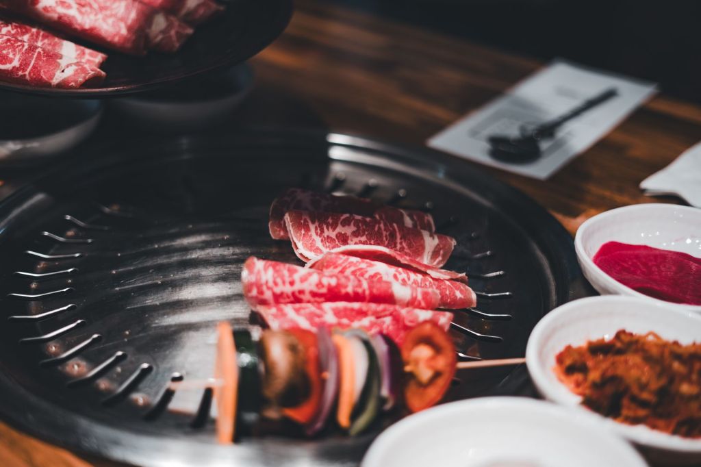 Thinly sliced beef and vegetables cooking on a Korean BBQ grill