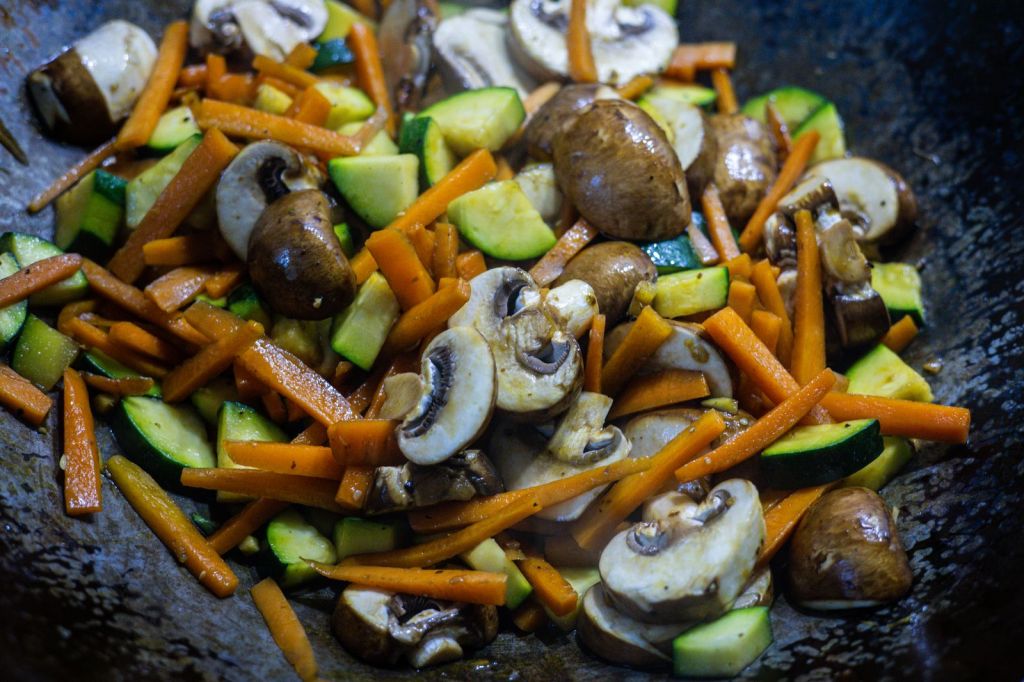 Stir-fried mushrooms, carrots and zucchini in a wok
