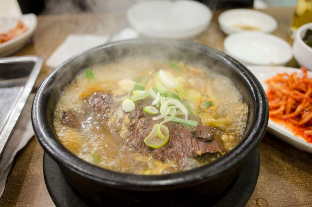 Steaming Korean beef soup in a hot stone pot garnished with scallions