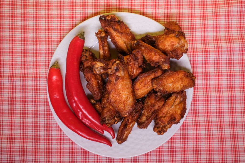 Crispy fried chicken pieces with sliced red chili peppers on a plate